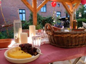 ein Tisch mit einem Teller Essen und einem Korb Wein in der Unterkunft Botanische Botschaft in Strodehne