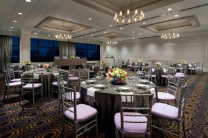 um salão de banquetes com mesas longas, cadeiras e lustres em Courtyard by Marriott Boston Cambridge em Cambridge