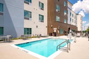 a swimming pool with chairs and a building at TownePlace Suites Austin South in Austin