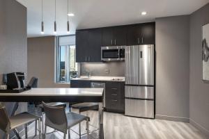 a kitchen with a stainless steel refrigerator and a table at Residence Inn Boston Downtown/South End in Boston