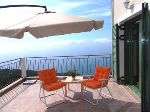 two chairs and a table on a balcony with an umbrella at Porto Katsiki Blu in Athani