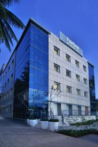 un gran edificio de cristal con plantas delante en Fairfield by Marriott Bengaluru Whitefield, en Bangalore