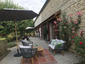 a patio with chairs and a table with an umbrella at Les Prés d'Allerey in Allerey-sur-Saone
