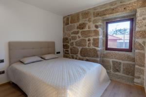- une chambre avec un lit et un mur en pierre dans l'établissement Carvalho Village, à Fafe