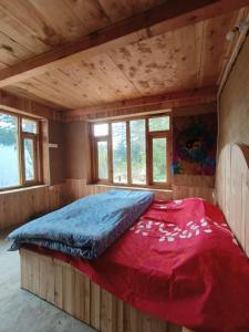 a large bed in a wooden room with a red blanket at Deep In Woods in Jibhi
