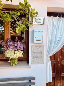 una ventana con un jarrón de flores púrpuras y blancas en Casetta Rocca en Rocca San Giovanni