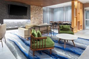 eine Hotellobby mit Stühlen, Tischen und einem TV in der Unterkunft Fairfield Inn & Suites by Marriott Atlanta Marietta in Marietta