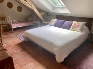 a bedroom with a large white bed with purple pillows at La Gironnerie in Loché-sur-Indrois