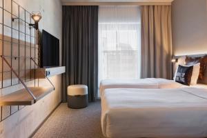 a hotel room with two beds and a window at Moxy Hamburg City in Hamburg