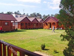 een persoon die voor een rij houten hutten loopt bij Domki Letniskowe Pikamar in Darlowko