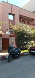 une moto garée devant un bâtiment rose dans l'établissement Villa Saraya, à Mehdiya-Plage