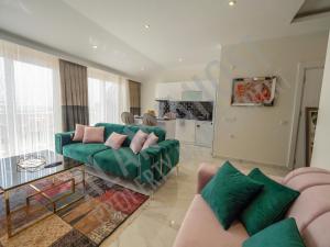 a living room with two green couches and a kitchen at Calypso Residence in Kestel Alanya C21 in Alanya