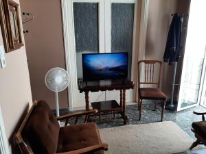 een woonkamer met een flatscreen-tv en een stoel bij Traditional Stone House with breathtaking view. in Zakharo