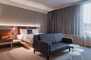 a hotel room with a bed and a chair at Moxy Frankfurt City Center in Frankfurt/Main