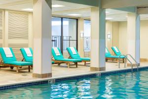 uma piscina com espreguiçadeiras azuis ao lado de uma piscina em Boston Marriott Newton em Newton