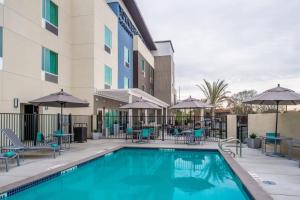 a pool at a hotel with chairs and tables and umbrellas at TownePlace Suites by Marriott Merced in Merced