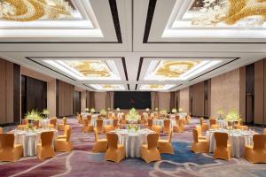 uma grande sala com mesas, cadeiras e tectos em Xiamen Marriott Hotel Haicang em Xiamen