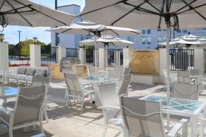 eine Terrasse mit Tischen, weißen Stühlen und Sonnenschirmen in der Unterkunft Element Austin Round Rock in Round Rock