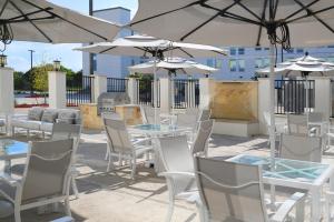 un patio con mesas, sillas blancas y sombrillas en Element Austin Round Rock en Round Rock