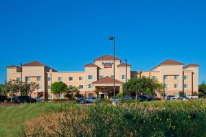 Fairfield Inn & Suites Fresno Clovis في كلوفيس: مبنى كبير به سيارات تقف في موقف للسيارات