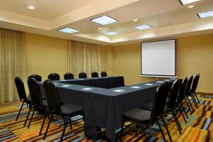 a conference room with a table and chairs and a screen at Fairfield Inn & Suites Fresno Clovis in Clovis