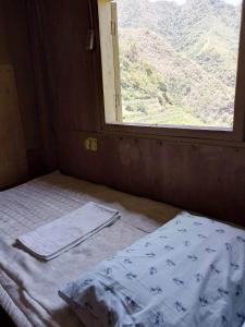 バナウェにあるBatad Family Inn and Hidden Hutのベッドと窓が備わる小さな客室です。
