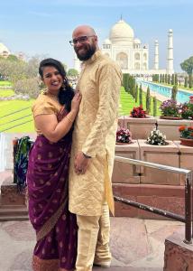 Ein Mann und eine Frau stehen vor einem Gebäude in der Unterkunft The Taj Homes in Agra