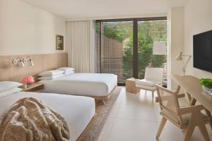 a hotel room with two beds and a desk and a television at The West Hollywood EDITION in Los Angeles