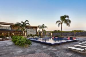 a swimming pool with palm trees and a building at Aloft Queretaro in Querétaro