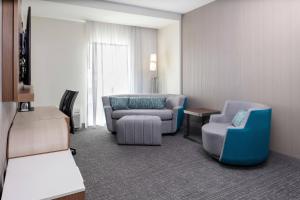 a room with two chairs and a couch and a table at Courtyard by Marriott Indianapolis West-Speedway in Indianapolis