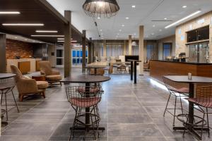 un hall avec des tables et des chaises ainsi qu'un bar dans l'établissement Courtyard by Marriott Indianapolis West-Speedway, à Indianapolis