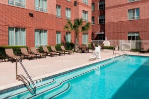 a swimming pool in a courtyard with chairs and a building at Residence Inn Houston West Energy Corridor in Houston