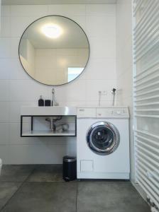 een wasmachine in de badkamer met een spiegel bij Duinkant in Groet