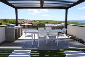 a patio with a table and chairs on a roof at Apartments Terra Sun with Private Pool or Jacuzzi in Njivice