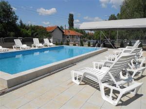 a group of white lounge chairs and a swimming pool at Apartments Milsa Lux in Soko Banja