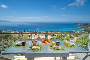 una mesa con comida y bebida en un balcón con vistas al océano en Κefalonia Golden View Villa en Kefallonia