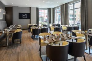 um restaurante com mesas, cadeiras e janelas em AC Hotel by Marriott Boston North em Medford