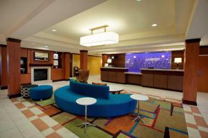 a lobby with a blue couch and tables and a tv at Fairfield Inn & Suites by Marriott Detroit Metro Airport Romulus in Romulus