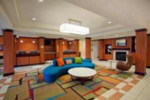 een grote woonkamer met een blauwe bank en tafels bij Fairfield Inn & Suites by Marriott Detroit Metro Airport Romulus in Romulus