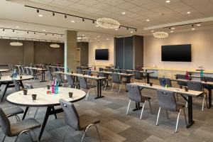 a conference room with tables and chairs and a screen at Aloft Fort Worth Trophy Club in Trophy Club