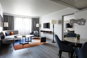 a living room with a table and chairs and a living room at Paris Marriott Charles de Gaulle Airport Hotel in Roissy-en-France +54 photos