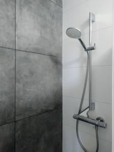 een douche met een douchekop in de badkamer bij Duinkant in Groet