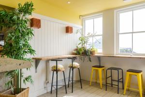 a bar with yellow stools in a room with windows at The Godolphin Hotel in Marazion