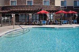 a swimming pool in front of a hotel with chairs and umbrellas at TownePlace Suites Columbia Southeast / Fort Jackson in Columbia