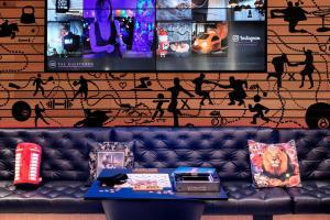 a couch in front of a wall with a tv at Moxy London Stratford in London