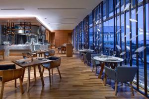 un restaurante con mesas, sillas y ventanas grandes en Kota Kinabalu Marriott Hotel, en Kota Kinabalu