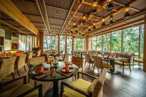 un restaurante con mesas, sillas y ventanas grandes en Renaissance Phuket Resort & Spa, en Mai Khao Beach