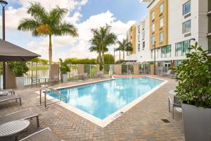 a swimming pool with patio furniture and palm trees at TownePlace Suites Miami Kendall West in Kendall