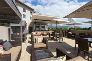 un patio al aire libre con sillas, mesas y sombrillas en Courtyard by Marriott Kingston, Jamaica, en Kingston