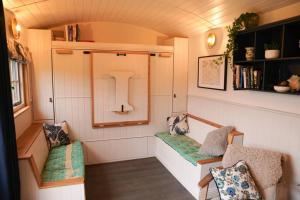 Shepherds Hut in countryside near Bath and Bristol في بريستول: غرفة صغيرة مع كرسيين في منزل صغير